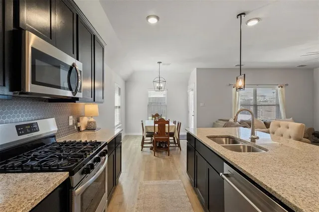 a kitchen with kitchen island granite countertop a stove a sink a kitchen island with a dining table and chairs