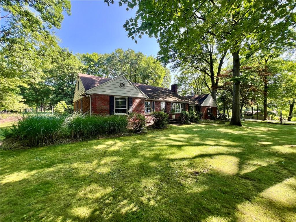 a view of a house with a big yard and large trees