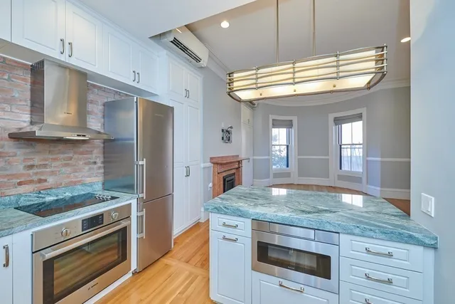 a kitchen with kitchen island granite countertop a stove and a wooden floors