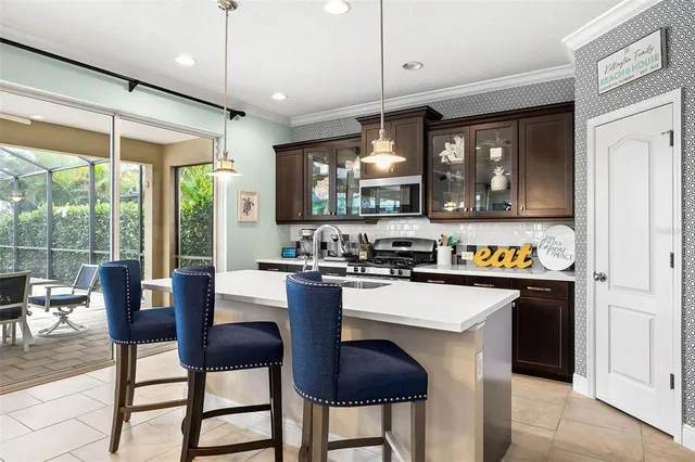 a kitchen with stainless steel appliances granite countertop a stove a refrigerator a kitchen island a dining table and chairs