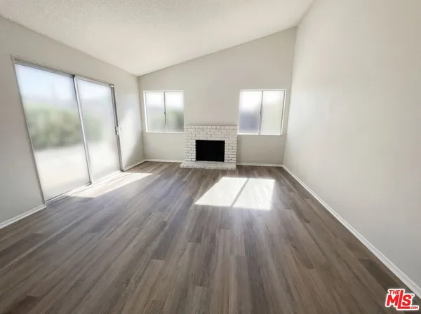 an empty room with wooden floor and fireplace