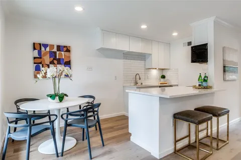 a kitchen with stainless steel appliances a dining table chairs refrigerator and microwave