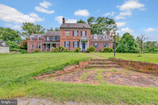 a view of a big house with a big yard and large trees
