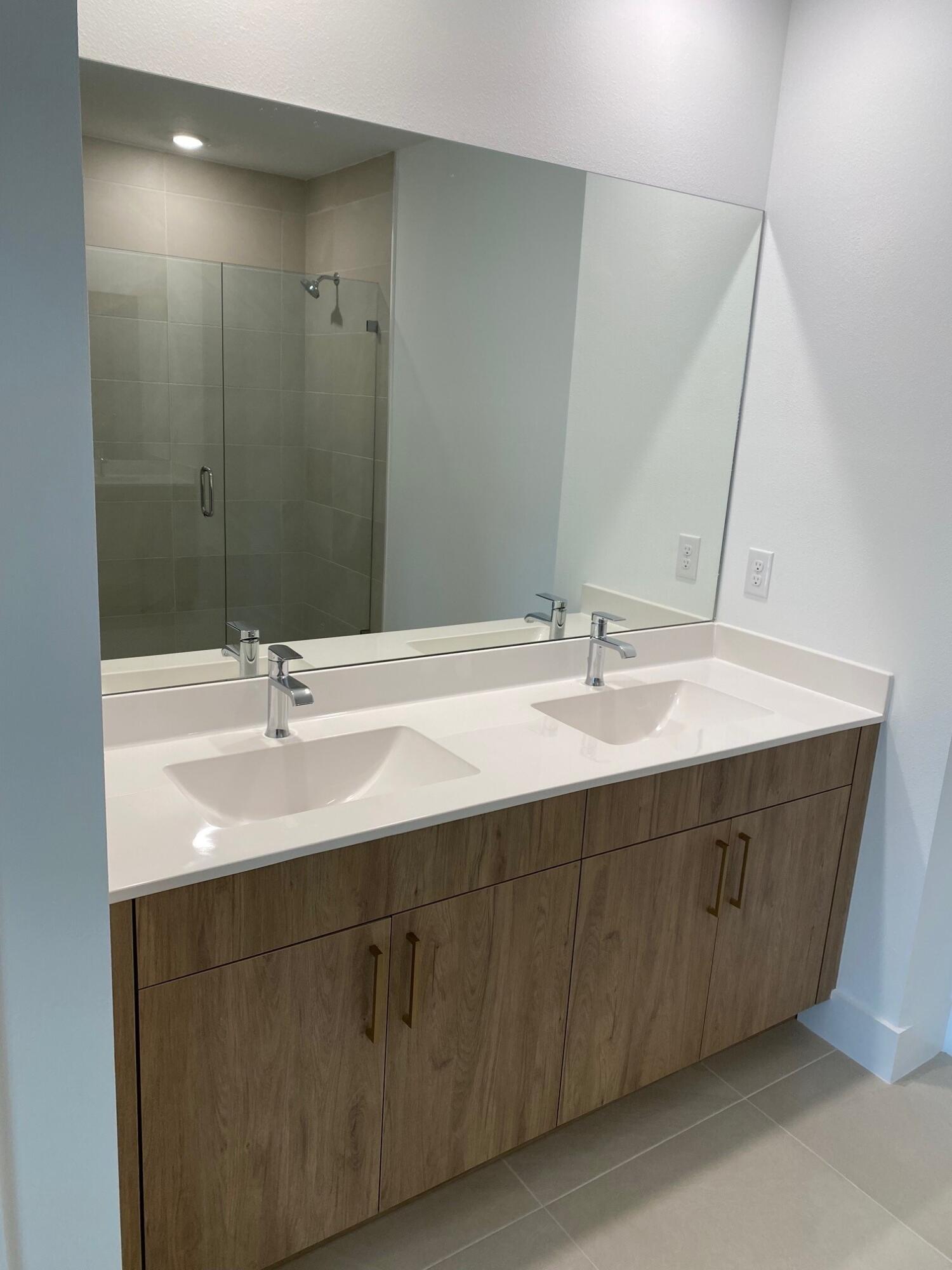 7011 Southeast Park Trace Drive Stuart, FL 34997 - Photo 14 of 19 a bathroom with a double vanity sink and mirror