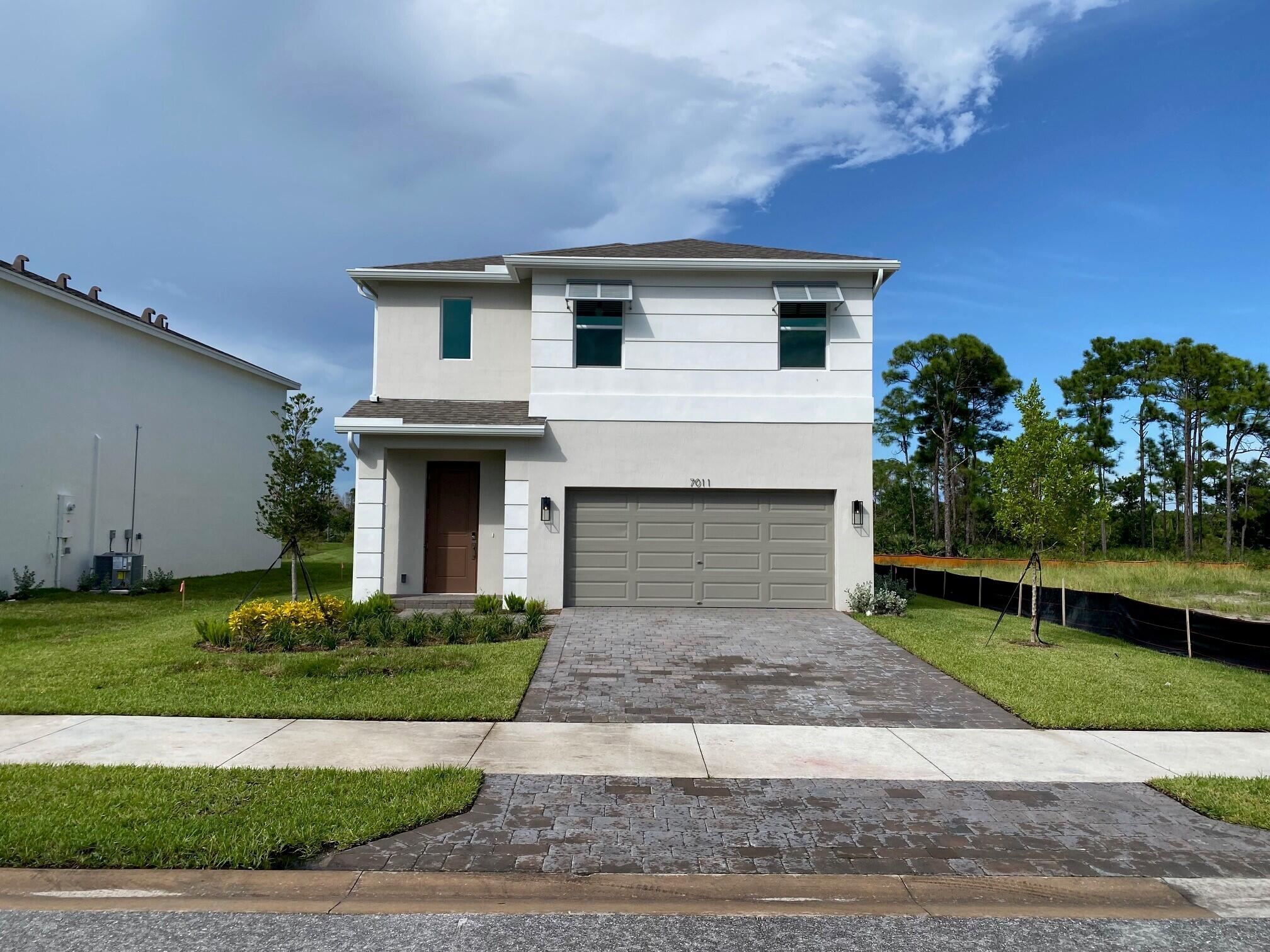 7011 Southeast Park Trace Drive Stuart, FL 34997 - Photo 2 of 19 a front view of a house with a garden and plants
