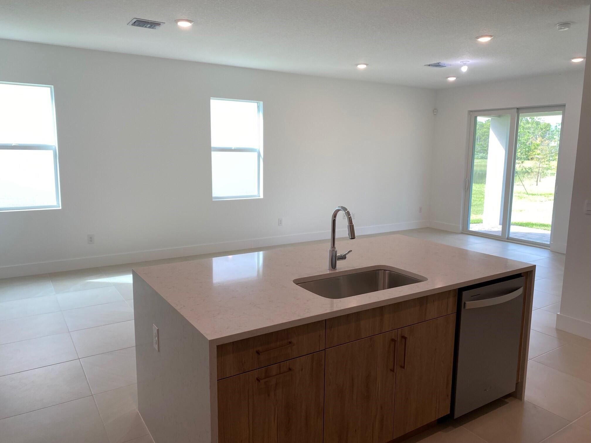 7011 Southeast Park Trace Drive Stuart, FL 34997 - Photo 6 of 19 a kitchen with kitchen island a sink and wooden cabinets