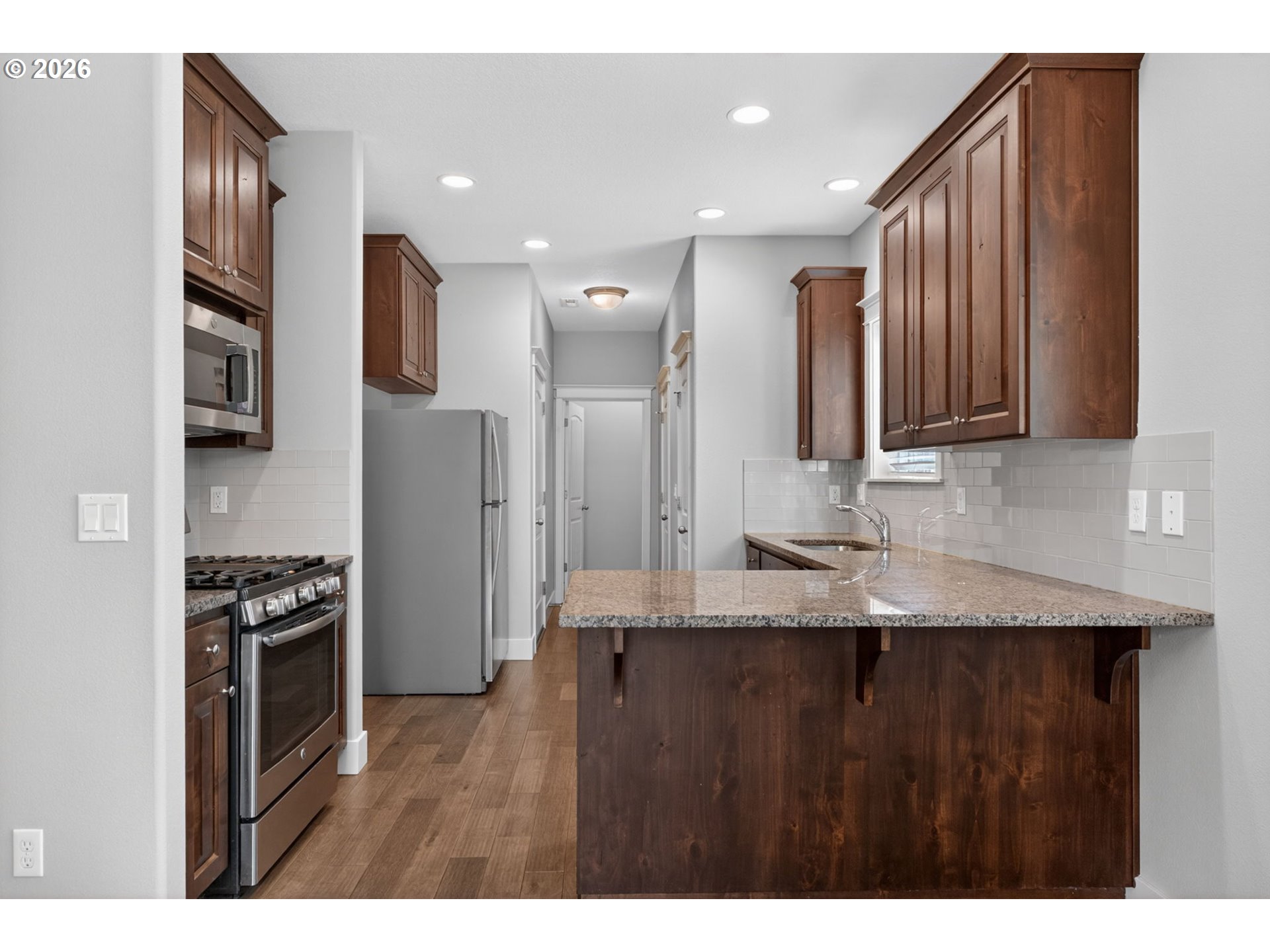 410 Rentfro Way Newberg, OR 97132 - Photo 9 of 39 a kitchen with stainless steel appliances granite countertop a refrigerator a sink dishwasher and wooden cabinets with wooden floor