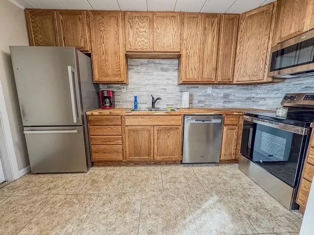 a kitchen with stainless steel appliances granite countertop a refrigerator stove top oven a sink and dishwasher