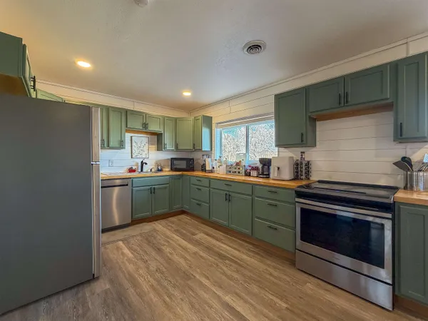 a kitchen with stainless steel appliances granite countertop a refrigerator sink and wooden cabinets