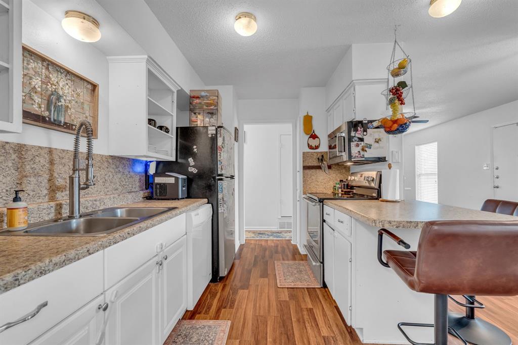 3800 Redstone Road Denton, TX 76209 - Photo 21 of 33 a kitchen with stainless steel appliances granite countertop a refrigerator a sink dishwasher a dining table and chairs with wooden floor