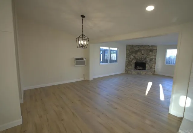 an empty room with wooden floor fireplace and windows