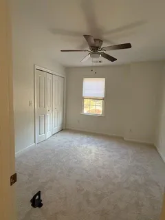 an empty room with windows and fan