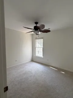 en empty room with windows and ceiling fan