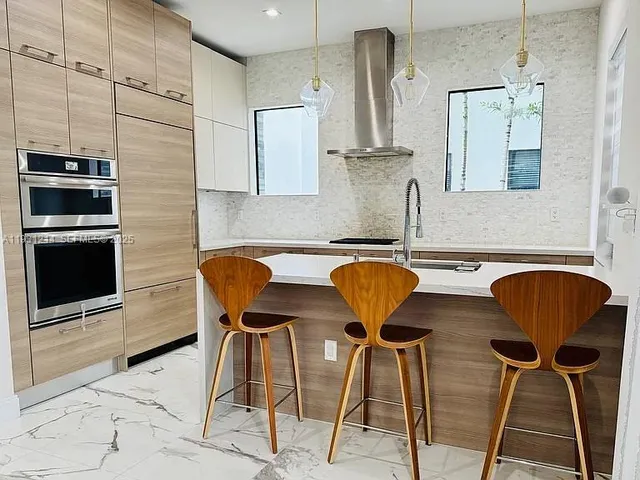 a kitchen with stainless steel appliances granite countertop a table chairs and a refrigerator