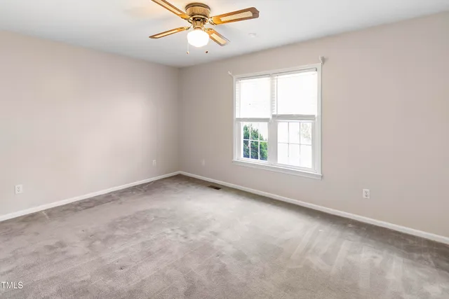 an empty room with a window and a fan