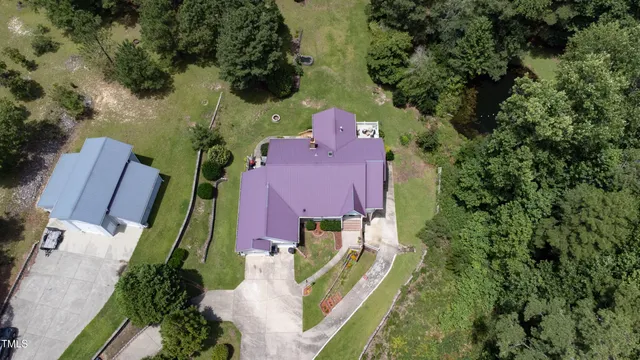 an aerial view of a house with outdoor space and trees all around