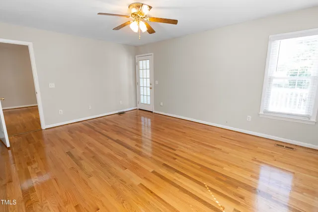 a view of an empty room with wooden floor and a window
