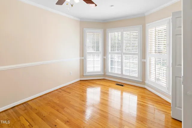 a view of an empty room with a window and wooden floor