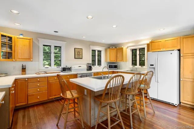 a kitchen with stainless steel appliances granite countertop a dining table chairs refrigerator sink and cabinets