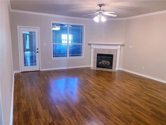 a view of an empty room with wooden floor fireplace and a window