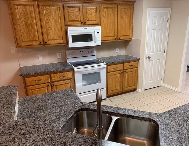 a kitchen with granite countertop a sink stove and microwave