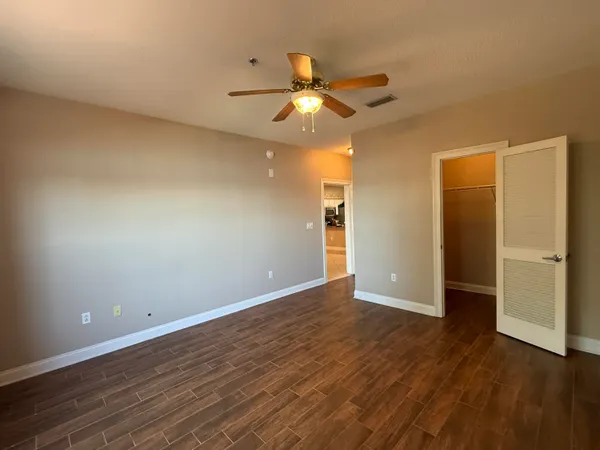 an empty room with wooden floor closet and ceiling fan