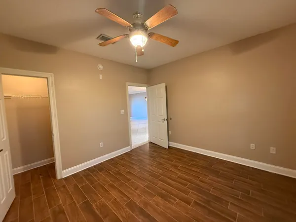 an empty room with wooden floor and a ceiling fan
