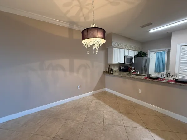 a view of a room with a chandelier fan and kitchen view