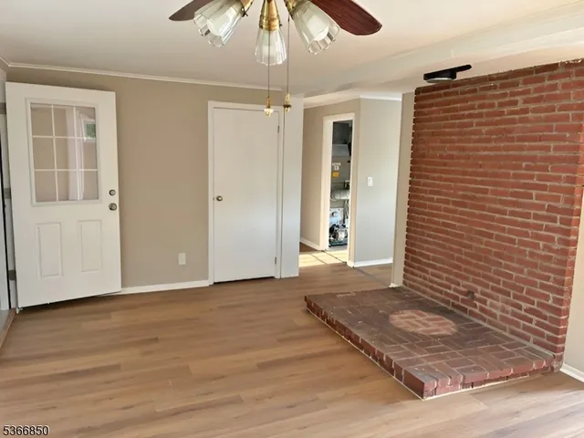 a view of an empty room with window and wooden floor
