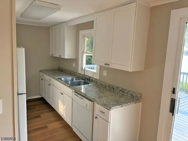 a kitchen with granite countertop a sink stove and cabinets