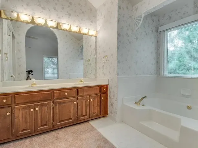 an empty room with chandelier fan and windows