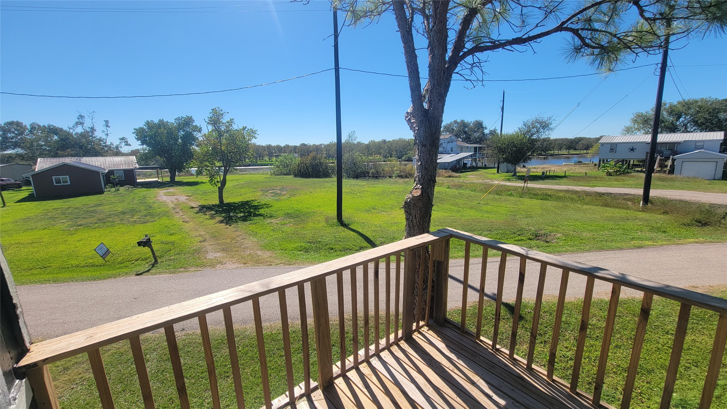 12018 Sandpiper Road Angleton, TX 77515 - Photo 7 of 48 A cozy balcony overlooks a quiet neighborhood street with green lawns and scattered trees. The view includes nearby houses and a glimpse of water in the distance, offering a peaceful, suburban feel.