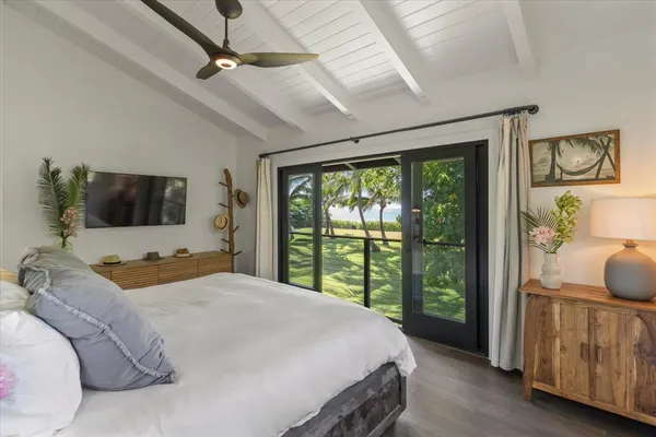 a bedroom with a large bed and a flat tv screen on dresser