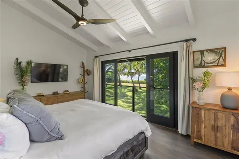 a bedroom with a large bed and a flat tv screen on dresser