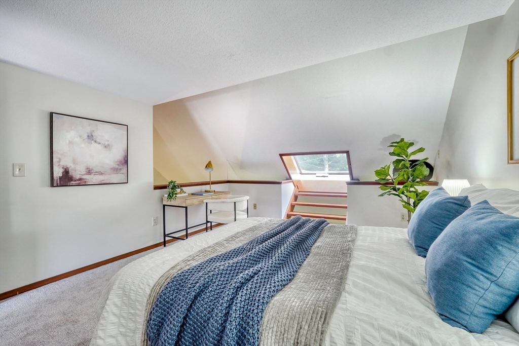 422 Great Elm Way, Unit 422 Acton, MA 01718 - Photo 15 of 30 a bedroom with a bed lamp and paintings on the wall