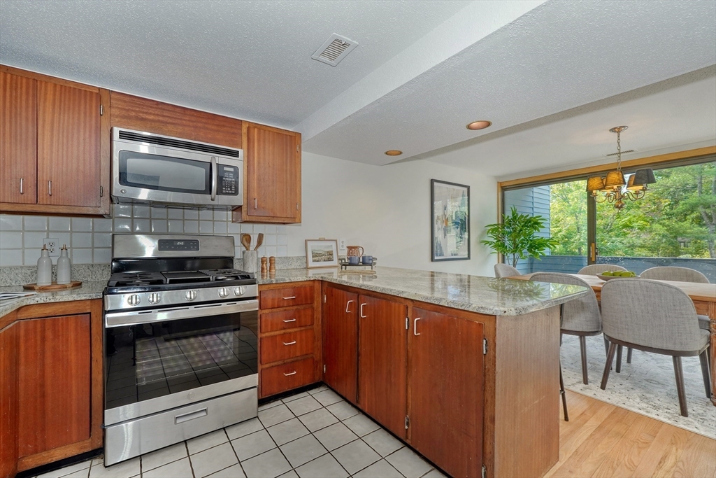 422 Great Elm Way, Unit 422 Acton, MA 01718 - Photo 23 of 30 a kitchen with stainless steel appliances granite countertop a stove a sink and a microwave