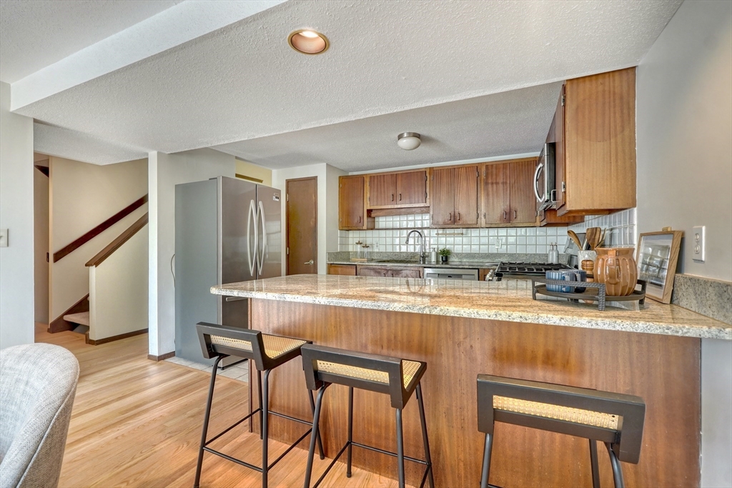 422 Great Elm Way, Unit 422 Acton, MA 01718 - Photo 3 of 30 a kitchen with stainless steel appliances granite countertop a refrigerator a sink dishwasher a stove and a dining table with wooden floor