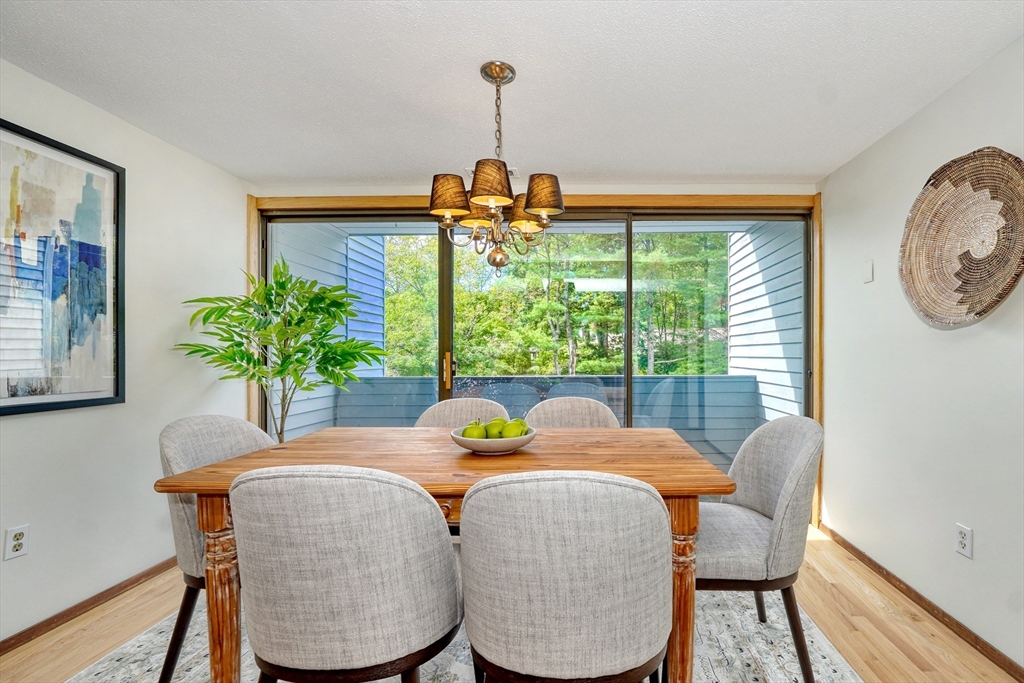 422 Great Elm Way, Unit 422 Acton, MA 01718 - Photo 5 of 30 a dining room with furniture a potted plant and a chandelier
