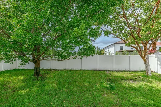 a view of a backyard with large trees and a barn