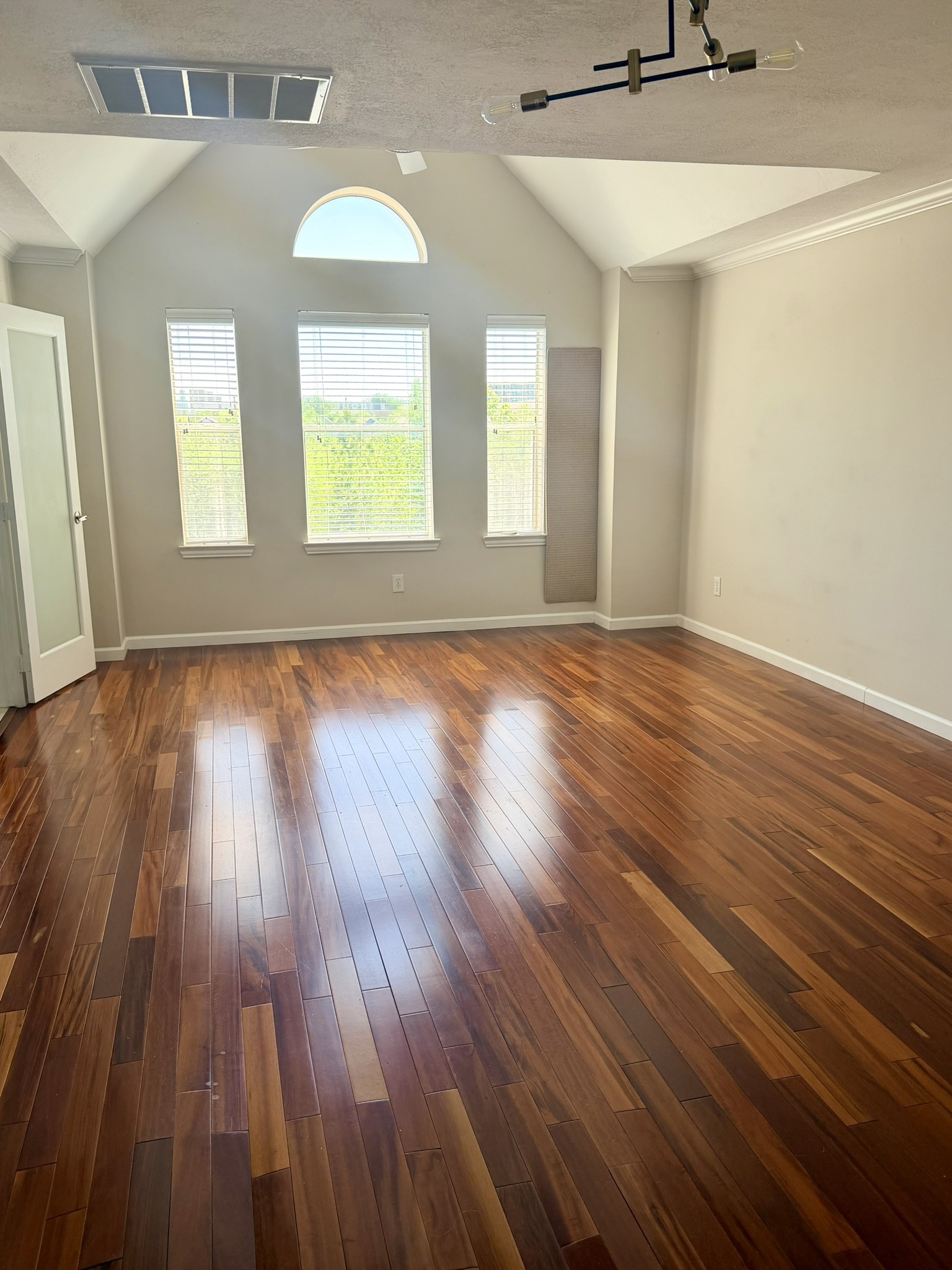 a view of an empty room with wooden floor and a window