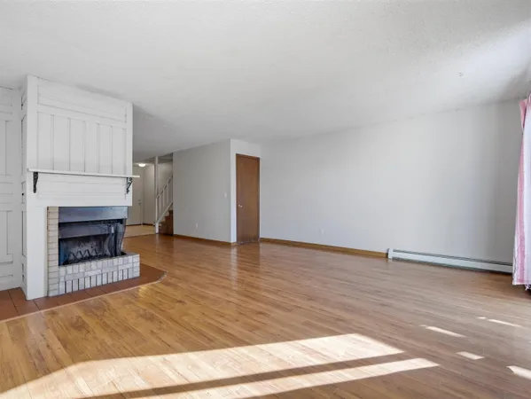 a view of empty room with wooden floor and fireplace
