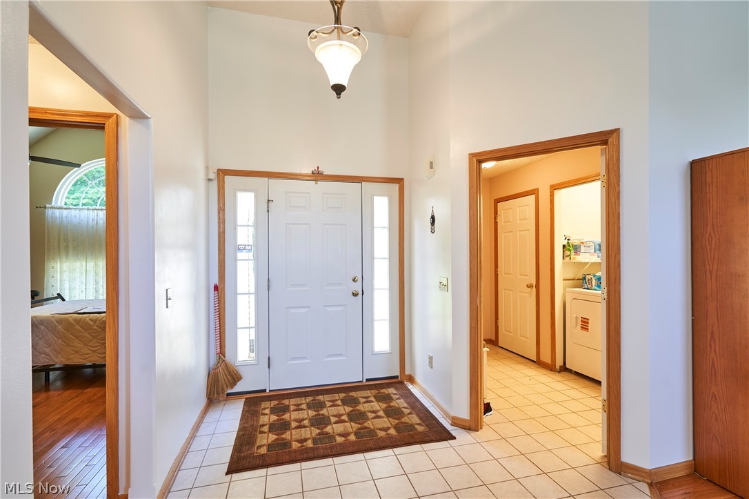 1963 Haines Road Madison, OH 44057 - Photo 7 of 34 Foyer with tile flooring, a vaulted ceiling, and a prominent front entry door featuring sidelights