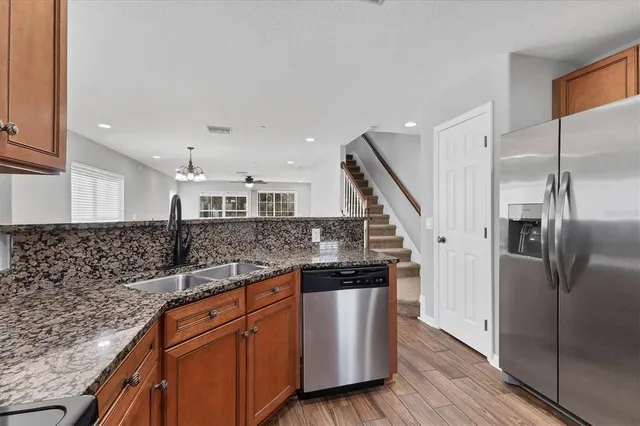 a kitchen with stainless steel appliances granite countertop a sink and a refrigerator