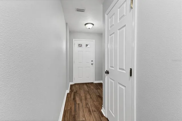 a view of a hallway with wooden floor and a bathroom