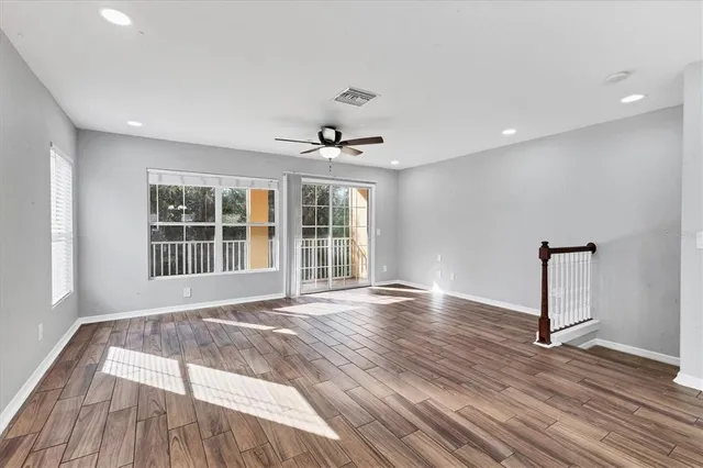 a view of an empty room with a window and wooden floor