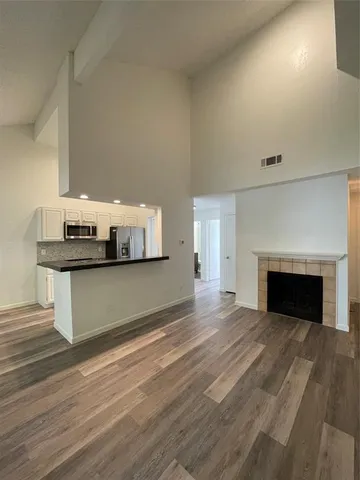 a view of an empty room with wooden floor and a fireplace
