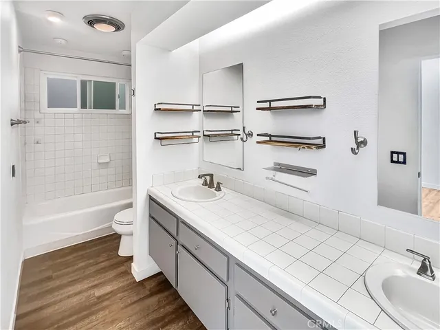 a bathroom with a double vanity sink toilet mirror and bathtub
