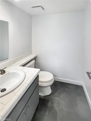 a bathroom with a granite countertop toilet and a sink