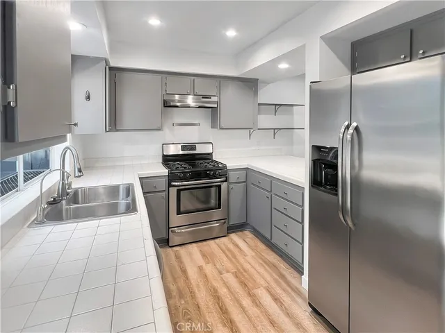 a kitchen with stainless steel appliances kitchen island granite countertop a refrigerator and a stove top oven