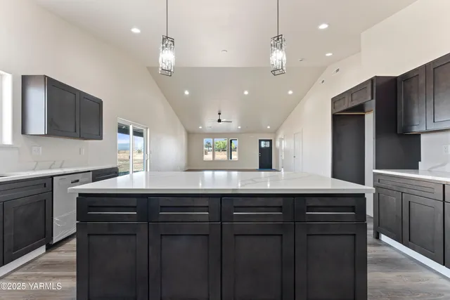 a kitchen with kitchen island granite countertop a sink and a refrigerator